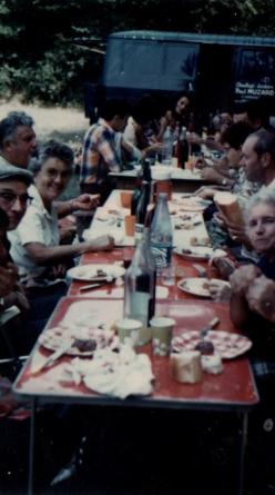 People gathered around a long table sharing food and natural wine