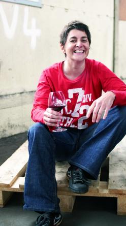 Isabelle Legeron laughing, wearing a red top, with a glass of wine