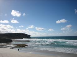 A wide sandy beach and coastline under a blue sky