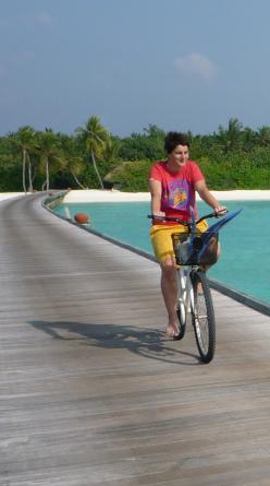 Isabelle Legeron cycling along a palm-lined tropical boardwalk