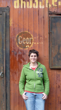 Isabelle Legeron in a green top standing by a rustic orange door