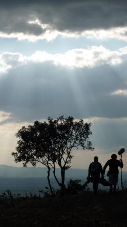 Two figures on a hillside under a dramatic cloudy sky